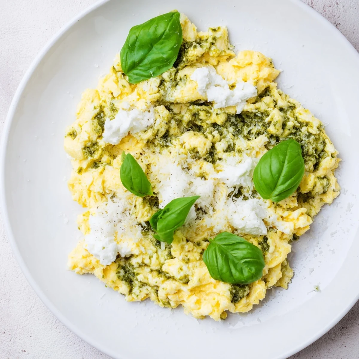 Fluffy Pesto Cottage Cheese Eggs, a vibrant breakfast, garnished with fresh basil and Parmesan cheese.