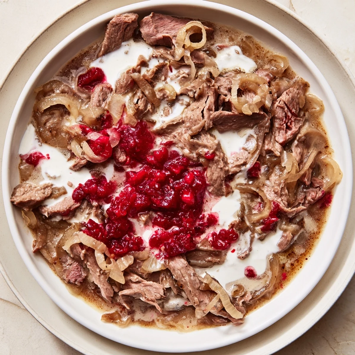 Tender Finnish Reindeer Stew, served steaming with mashed potatoes and bright red lingonberries.