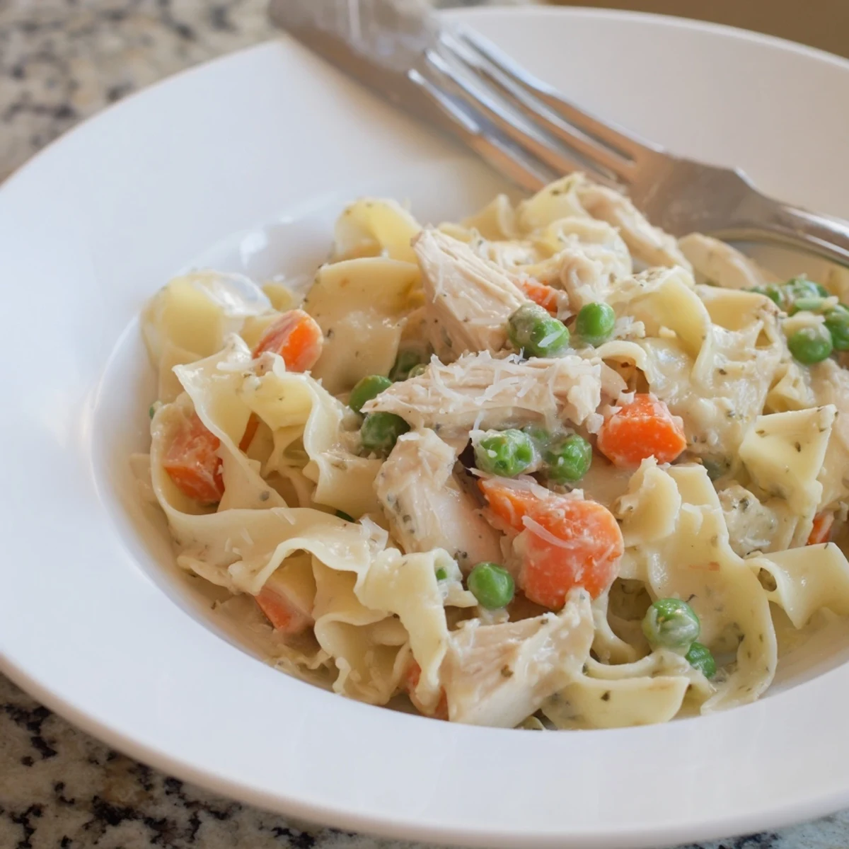 Creamy Spring Chicken Noodle Skillet with tender shredded chicken, sweet peas, and bright carrots, served in a warm skillet.  