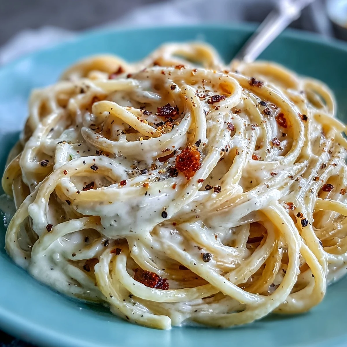 Creamy Cacio e Pepe pasta twirled on a fork, topped with extra Pecorino Romano and black pepper.
