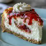 Freshly sliced Easy Guava Swirl Cheesecake shows creamy filling and pink tropical fruit sauce drizzled on top. 
