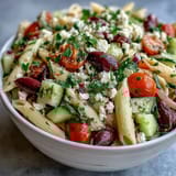 A colorful Greek pasta salad with feta, olives, and fresh vegetables, perfect for summer picnics.