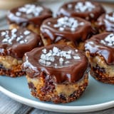 Chocolate cups with pretzel crust and peanut butter filling, topped with a glossy chocolate layer and festive sprinkles.