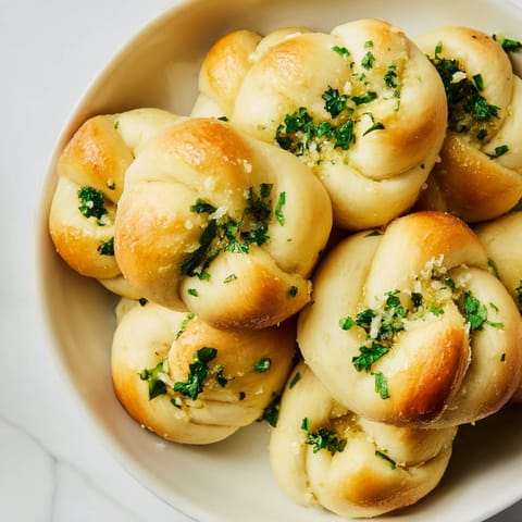 Freshly baked homemade garlic knots, perfectly knotted and glistening with savory garlic butter and herbs.