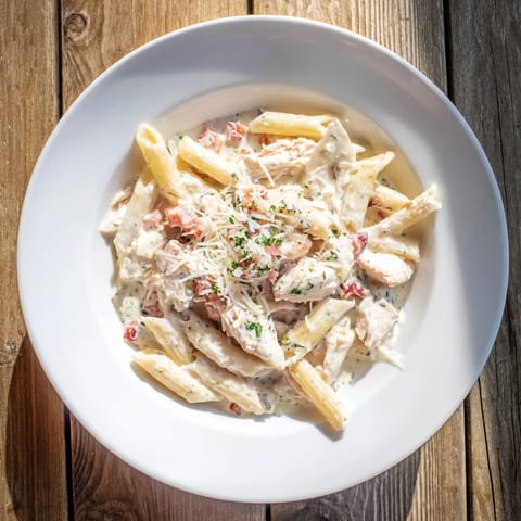 Golden, glistening Tini's Creamy Chicken Pasta, garnished with fresh parsley and extra Parmesan cheese.