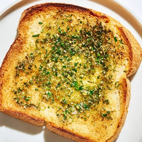 Warm Herb Butter Toast on a plate with fresh herbs, ready for an appetizing snack.