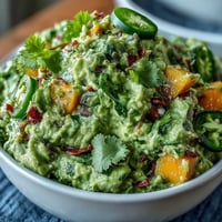 Creamy Cinco de Mayo guacamole with juicy mango and spicy jalapeño, perfect for festive snacking.  