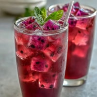 Refreshing mango dragonfruit refresher with vibrant tropical fruit and citrus, served over ice for a cool summer treat.